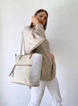 Bolso tipo tote bag color beige con laterales estampados y detalles en cuero marrón.