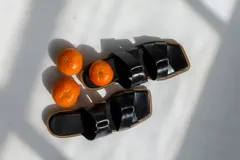 Sandalias negras con tiras anchas cruzadas y detalle de nudo.