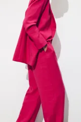 Pantalón de tiro alto color fucsia, con bolsillos delanteros y falsos bolsillos de vivo en la espalda. Tejido con efecto arrugado, pernera recta y cierre frontal con cremallera, botón interior y gancho.