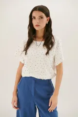 Blusa blanca con estampado de lunares negros, de corte holgado y manga corta.