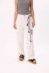 Pantalón cargo color crudo, de denim liviano, con tiro medio, pierna amplia y bolsillos laterales. Incluye tiritas trenzadas con pañuelo estampado atadas a la cintura.