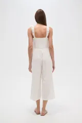 Mono de algodón blanco con bordado broderie, cuello cuadrado y volados en los breteles. Presenta un diseño entallado en el torso y pantalones de pierna ancha.