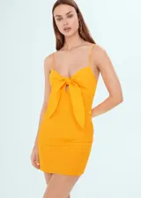 Vestido corto color amarillo, con tirantes finos, escote con nudo y cierre lateral con cremallera.