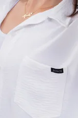 Camisa negra de corte amplio, con cuello clásico, cierre frontal con botones, manga larga con puños arremangados y bolsillo de parche en el pecho.