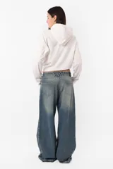 Buzo blanco de rústico, con capucha forrada y detalle de tira para frunce y hebilla en delantero. Mangas con recortes y mitón para dedo pulgar.