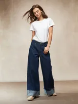 Jean de mezclilla azul oscuro, tiro alto, corte ancho y pierna recta muy amplia, con puños doblados que muestran el interior más claro.