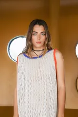 Vestido largo tejido en hilo de algodón color crudo, con calado y cuello redondo con ribete azul y mangas con ribete naranja.