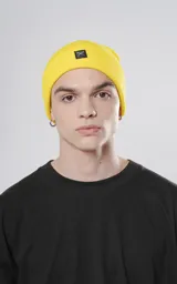Gorro de lana amarillo tejido con poliéster y acrílico, con logo de la marca en etiqueta negra.