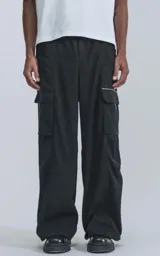 Pantalón cargo negro de corte ancho, con cintura elástica, cinturón con hebilla y múltiples bolsillos.
