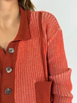 Saco de punto color crudo con cuello camisero, cierre frontal con botones y bolsillos de parche.
