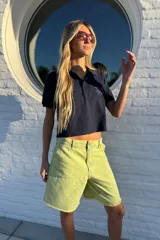 Bermuda de jean color marrón oscuro, tiro alto, con pinzas y ruedo desflecado.