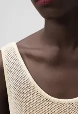 Musculosa de punto calado color crema, con escote redondo y sisas amplias. Tejido de malla con trama abierta.