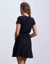 Vestido corto negro texturado con escote redondo, manga corta, lazo de ajuste en la cintura y ruedo con volados.