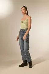 Pantalón de jean azul lavado, tiro alto, corte recto y largo. Presenta un patrón de rombos cosidos con hilo blanco o strass a lo largo de toda la prenda.