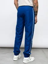 Pantalón deportivo negro de nylon con detalles en contraste blanco y logo de Umbro bordado en el lateral. Corte relajado.