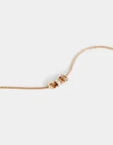 Collar corto dorado con cadena de eslabones cuadrados y dijes de arandelas con strass blancos y rosados.