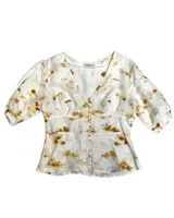 Camisa color amarillo pálido con corte en la cintura y abotonadura central. Tiene manga abullonada con detalle de elástico en puños.