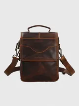 Maletín pequeño tipo bandolera o morral de cuero marrón oscuro con efecto envejecido. Posee asa superior y correa ajustable para llevar al hombro. Presenta un bolsillo frontal con solapa curva y el logo de Hush Puppies grabado.