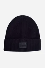 Gorro de lana color marrón con etiqueta negra con el logo de la marca en el frente. Tejido de punto acanalado.