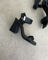 Sandalias plateadas con tira delantera, tobillera con hebilla y taco geométrico.