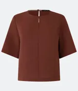 Blusa color ladrillo de mangas cortas confeccionada en crepé texturizado, con cuello redondo y abertura en la espalda. Corte recto y holgado.