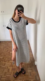 Vestido largo de tejido a rayas horizontales blancas y negras, con cuello redondo y ribete negro en el cuello y mangas cortas. Presenta un tajo lateral en la falda.