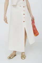 Falda midi color crudo con botones frontales y abertura en el centro.