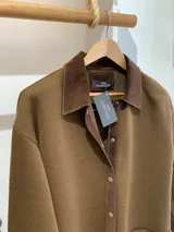 Camisa marrón de tejido de punto en lana con cuello y bolsillos de cuero, con cierre frontal de botones a presión.