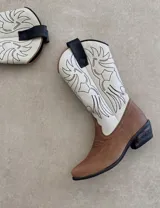 Botas de cuero negro con bordado decorativo en el caño y empeine, taco bajo y punta fina. Diseño de estilo cowboy.