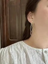 Set de accesorios de metal dorado con detalles en cuero marrón, que incluye un brazalete, aros, un collar y un broche. Se presenta en un sobre de cuero marrón con cierre de broche.