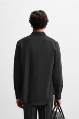 Camisa de vestir verde oscuro, corte slim fit, con cuello italiano, mangas largas con puños abotonados y cierre frontal con botones.