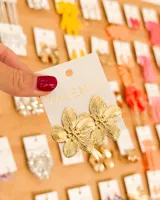 Par de aros tipo botón con forma de flor de cinco pétalos, con textura estriada en relieve y acabado dorado brillante.