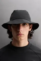 Sombrero tipo bucket color beige, confeccionado en tejido técnico con perforaciones en la copa para mejorar la transpirabilidad. Tiene ajuste elástico y ala ancha con pespuntes.