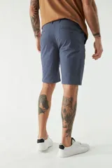 Bermuda de gabardina color beige, corte chino, con bolsillos laterales y traseros, cierre con cremallera y botón, presillas para cinturón y logo bordado.