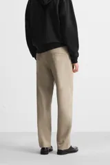 Pantalón chino color verde militar, de corte recto, con bolsillos laterales y traseros de vivo. Cierre frontal con cremallera y botón.