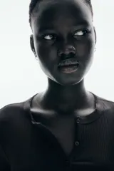 Remera ajustada de punto acanalado suave, color negro, con cuello redondo ribeteado en picot y tapeta de botones. Manga larga.