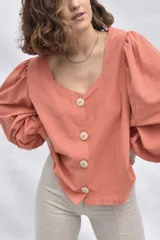 Camisa color salmón de muselina 100% algodón, con escote en V, mangas abullonadas 3/4 y cierre frontal con botones de madera.