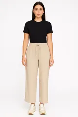 Pantalón ancho de tiro alto color crema, confeccionado en lino, con cintura elástica y cordón ajustable.