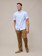 Camisa de algodón blanca de manga corta, con cuello abotonado y botones frontales.