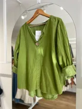Blusa verde manzana de pana fina con cuello en V y manga larga con puños arremangados.