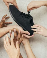 Zapatilla negra de lana merino con cordones y suela de EVA. Diseño minimalista y atemporal, sin género y para todas las edades.