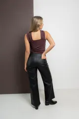 Pantalón de ecocuero negro con textura rústica, corte recto, bolsillos delanteros y traseros funcionales, cierre frontal con botón y cremallera.
