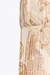 Vestido midi de cuello halter con estampado paisley en tonos beige, amarillo y marrón. Tiene lazada en la espalda, cintura elástica y falda plisada. Cierre trasero con cremallera oculta, abertura y botón.