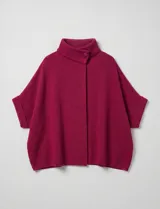 Capa o poncho tejido color verde esmeralda, con cuello polera alto que se cierra con un botón grande en el lateral. Presenta mangas cortas estilo japonesa y un calce amplio.