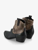 Botín de cuero negro y marrón, de estilo texano, con punta fina, costuras decorativas y taco bajo.