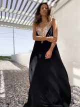Vestido largo negro con escote en V y apliques de lentejuelas doradas en el corpiño.