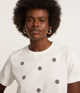 Remera de manga corta color blanco, con cuello redondo y bordados de flores en el frente.