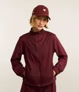 Campera deportiva rompevientos color bordó, con cuello alto, cierre frontal con cremallera, puños elastizados y recortes con hilo reflectante.