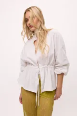 Chaqueta azul con cuello mao, mangas largas abullonadas y lazo en la cintura.