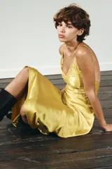 Vestido midi amarillo satinado con escote en pico, tirantes finos ajustables y detalle de encaje a tono en el escote y laterales.